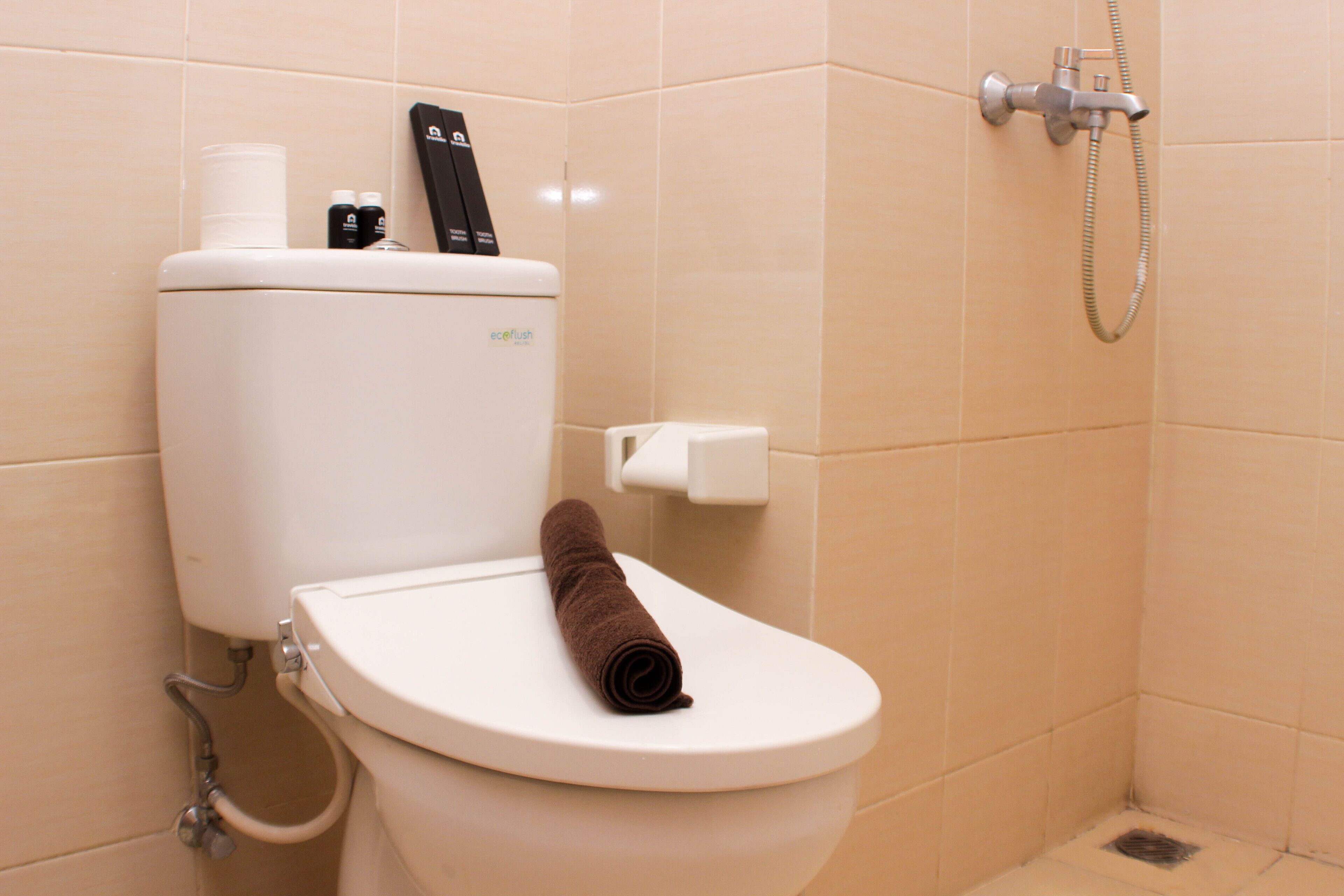 Des toilettes avec une serviette sur le siège, un porte-serviettes en papier et un distributeur de savon.