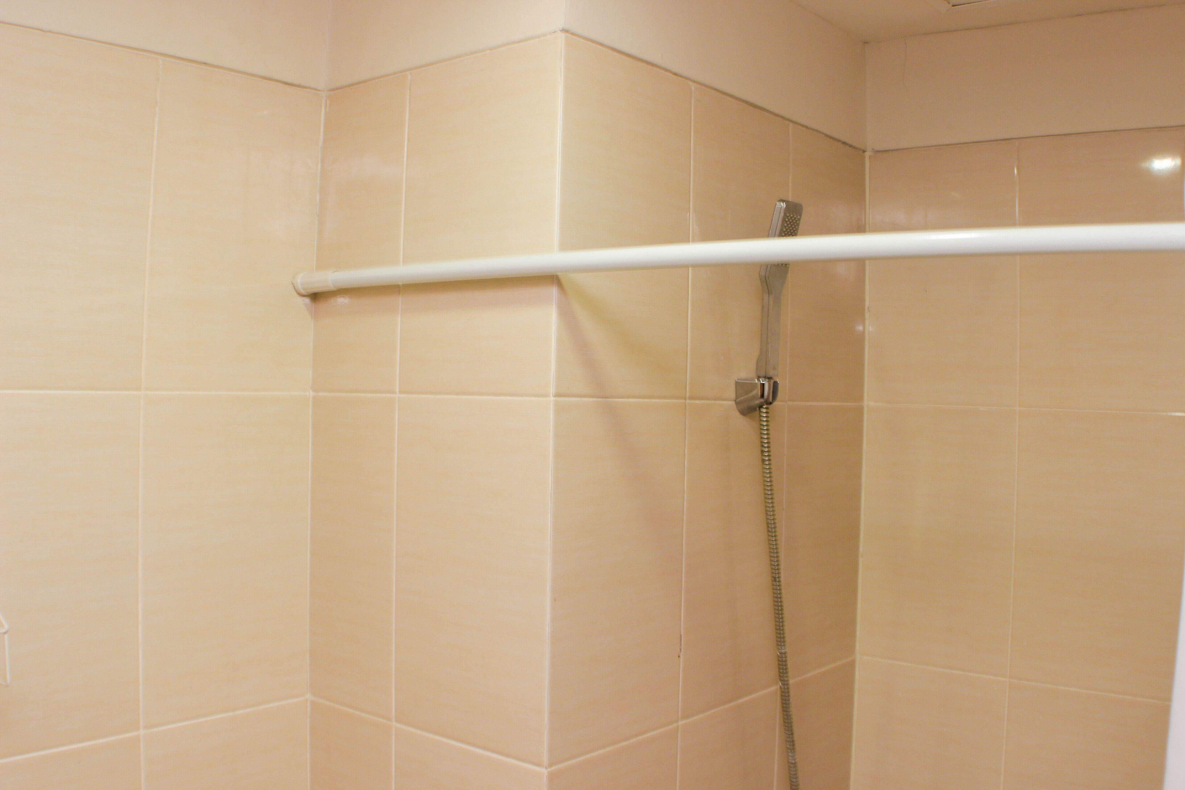 A shower with a white handrail and a showerhead.