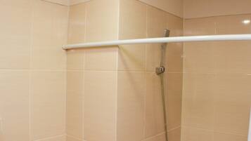 A shower with a white handrail and a showerhead.
