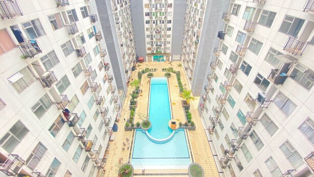Un edificio residencial alto con piscina central rodeada de balcones y terrazas.