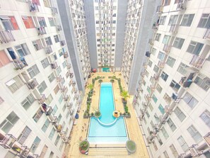 A high-rise residential building with a central swimming pool surrounded by balconies and terraces. - Cozy Living 2Br Apartment At Jarrdin Cihampelas (Bandung)
