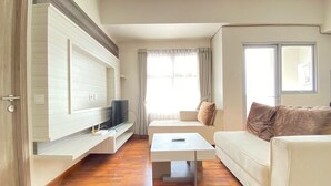 Ein modernes Wohnzimmer mit Flachbildfernseher an einer Wandnische, einem weißen Sofa, einem Couchtisch und Holzböden.