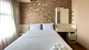 Ein Hotelzimmer mit einem Bett, einem Nachttisch, einem Spiegel und einer integrierten Schminkkommode mit Spiegel und Ablageflächen.