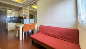 Ein kompakter Wohnbereich mit Küchenzeile, einem Essbereich mit Tisch und Stühlen sowie einem roten Sofa.