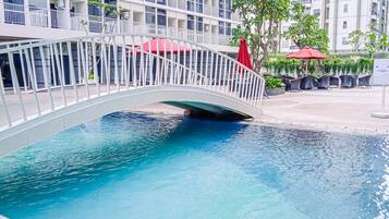 A swimming pool with a white bridge, surrounded by potted plants and outdoor seating.