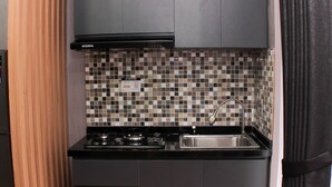 A compact kitchen with a gas stove, a sink, and a tiled backsplash. - Comfort And Restful 2Br At Bassura City Apartment (Jakarta)