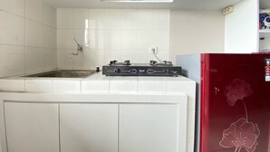 A kitchen with white cabinets, a red refrigerator, and a gas stove. - Cozy 2Br Apartment At Newton Residence Bandung (Bandung)