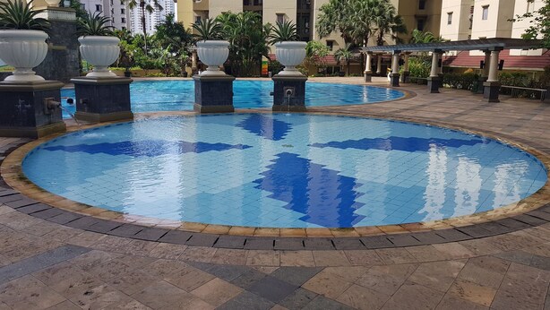 A circular pool with a tiled edge and a fountain in the center.