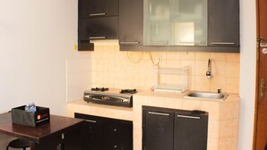 A compact kitchen with black cabinets, a built-in oven, a sink, and a small countertop.