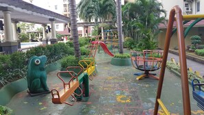 A playground with various play structures, including a seesaw, a slide, and a climbing frame.