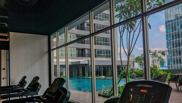 Une salle de sport avec des tapis de course et vue sur la piscine.
