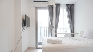 Une chambre d’hôtel avec un lit, un téléviseur fixé au mur, une fenêtre avec des rideaux et un balcon.