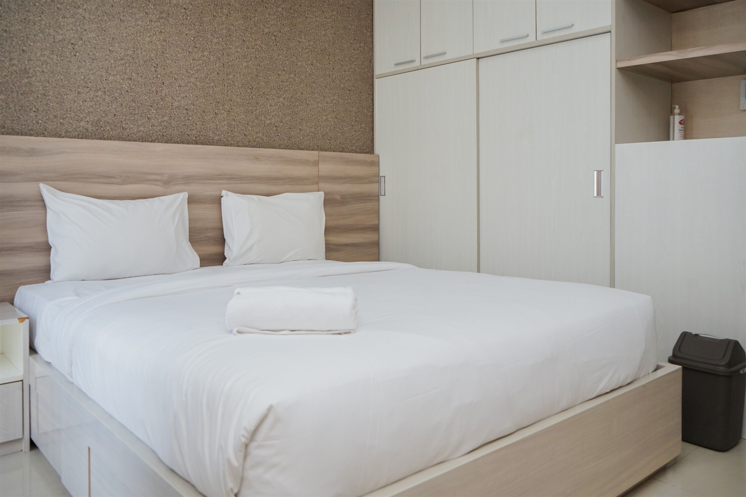 A neatly made bed with white linens, a wooden headboard, and a small bedside table with a lamp.