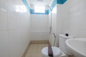 Ein kleines, sauberes Badezimmer mit weißen Fliesen, einer Toilette, einer Dusche und einem Waschbecken.