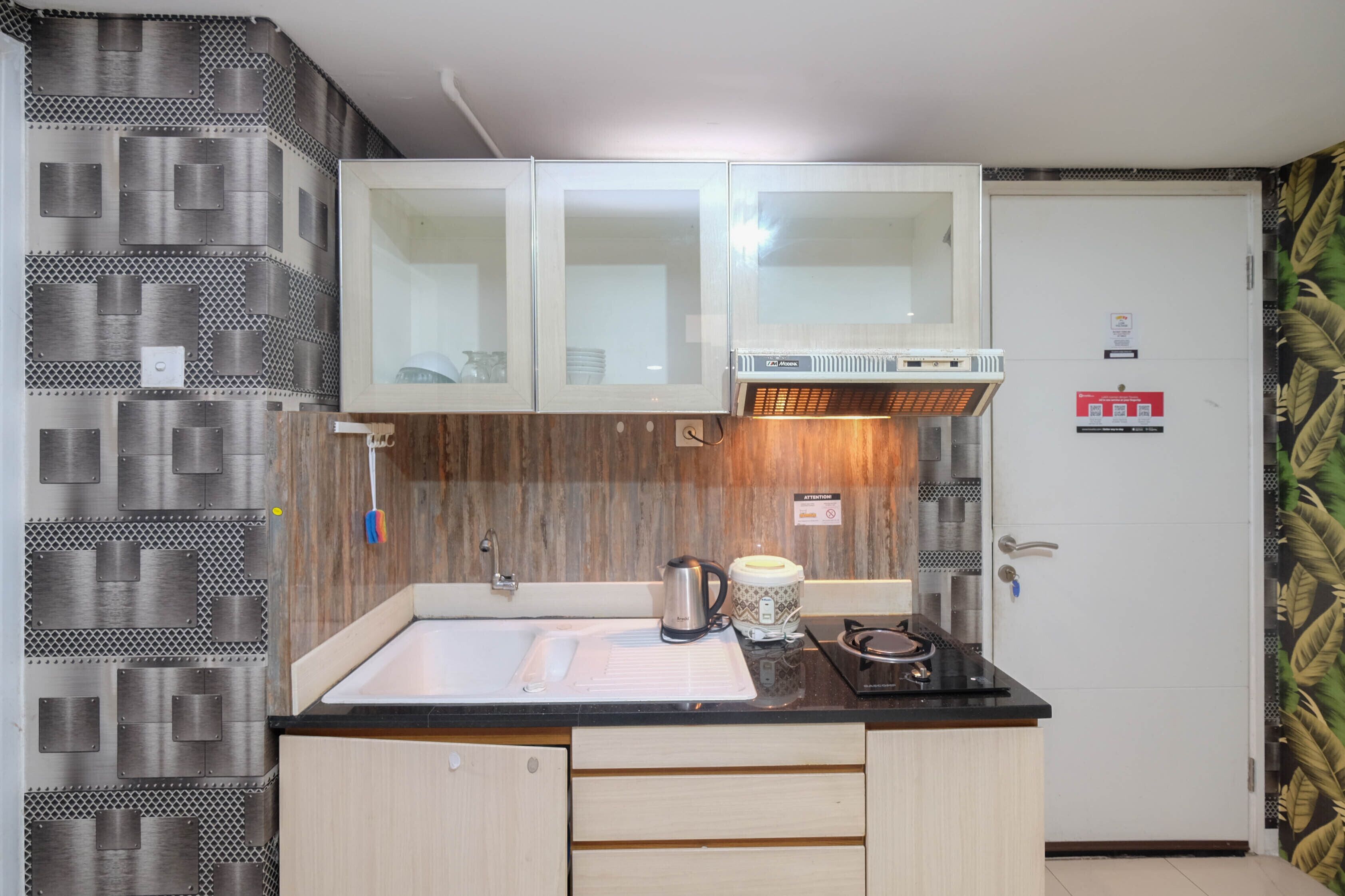 Una cocina compacta con un lavamanos, armarios y una cafetera.