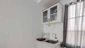 A small kitchenette with a white cabinet, a sink, and a dish rack. - Good Deal 1Br At Paltrow City Apartment (Semarang)