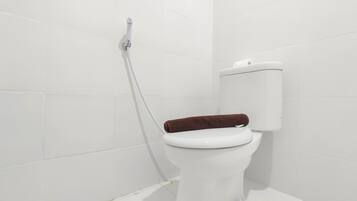 A white toilet with a brown seat in a bathroom with white tiled walls.