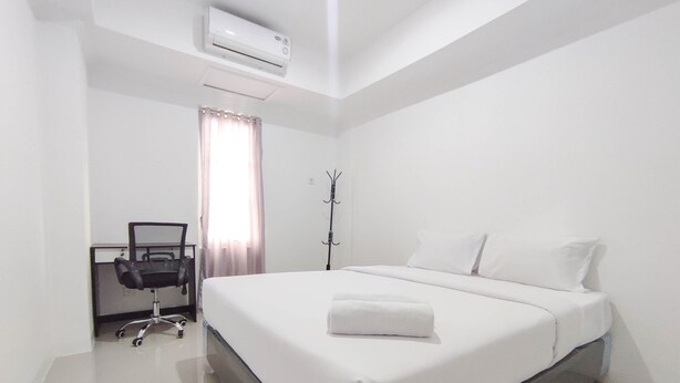 A clean, modern hotel room with a large bed, a desk, and an air conditioning unit. - Good Deal 1Br At Paltrow City Apartment (Semarang)