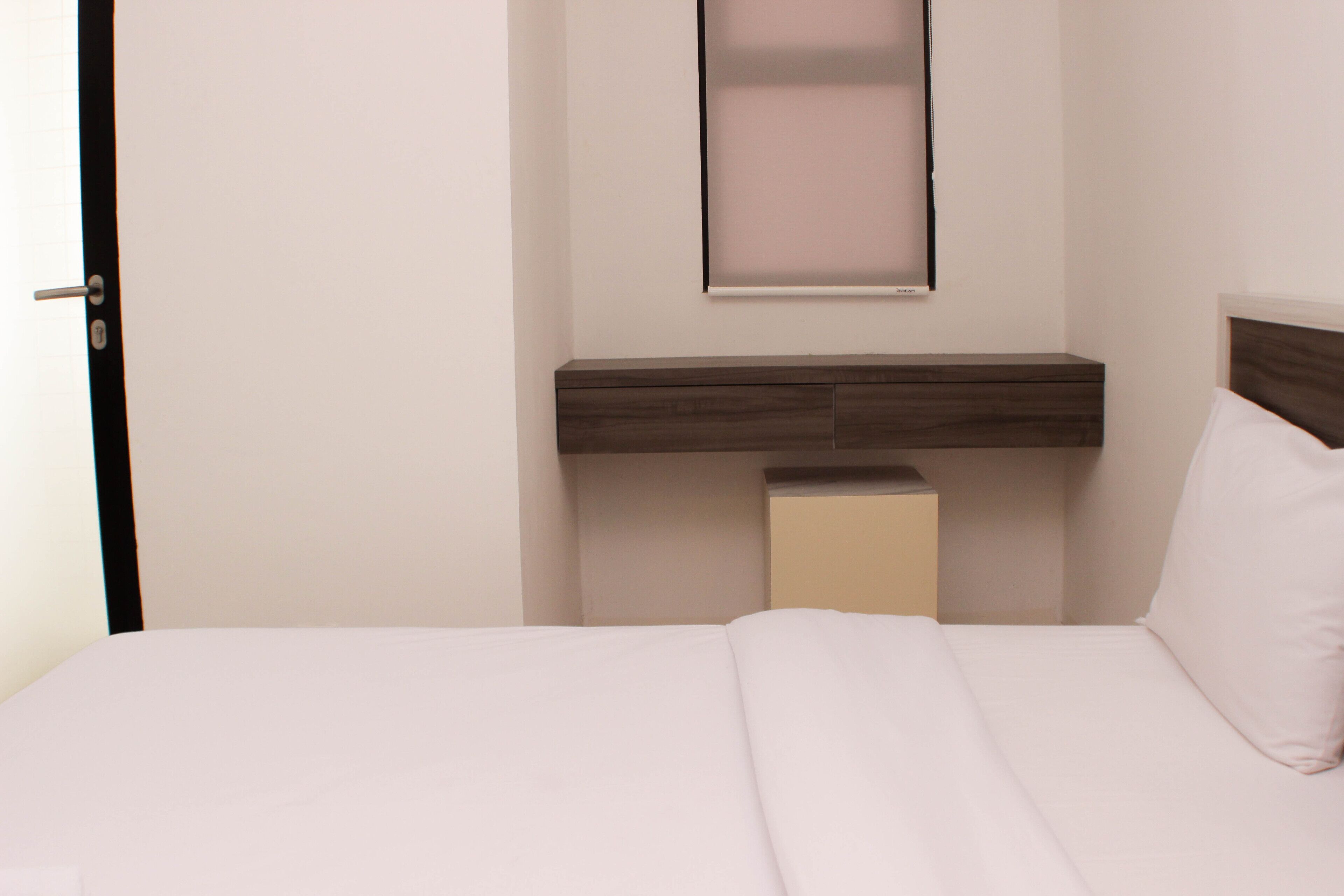 Un dormitorio con una cama, una mesita de noche, un tocador y un espejo en la pared.