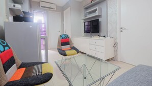 A compact living space with a kitchenette, a glass-top dining table, and a colorful chair. - Strategic And Restful 2Br At Bassura City Apartment (Jakarta)