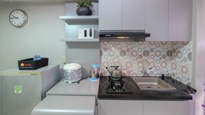 A compact kitchen with a microwave, toaster, coffee maker, and a sink. - Strategic And Restful 2Br At Bassura City Apartment (Jakarta)