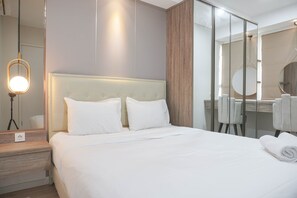 Une chambre d’hôtel avec un grand lit, une table de chevet, un miroir et une chaise.