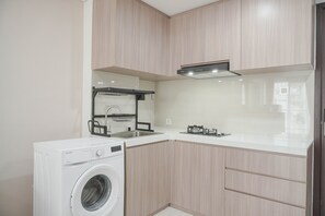 Une cuisine compacte équipée d’un lave-linge intégré, d’un évier et d’une cuisinière.