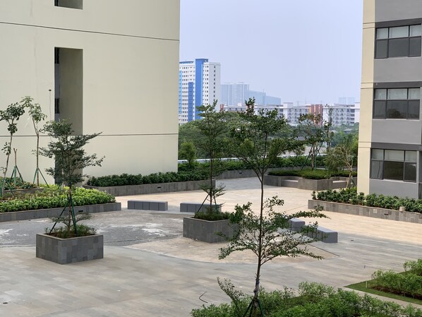 Une cour intérieure agrémentée d’arbres en pot et d’un chemin pavé, entourée de bâtiments modernes.
