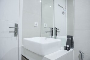 Une salle de bain moderne avec une grande baignoire blanche, une douche en verre et un miroir orné d’une inscription noire.