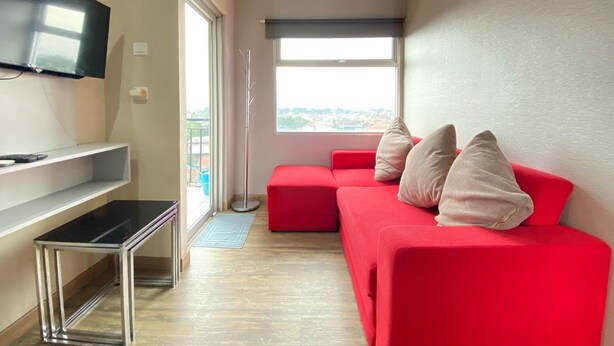 Ein modernes Wohnzimmer mit einem roten Sofa, einem flachbildfernseher an der Wand und einem großen Fenster mit Blick auf die Stadt.