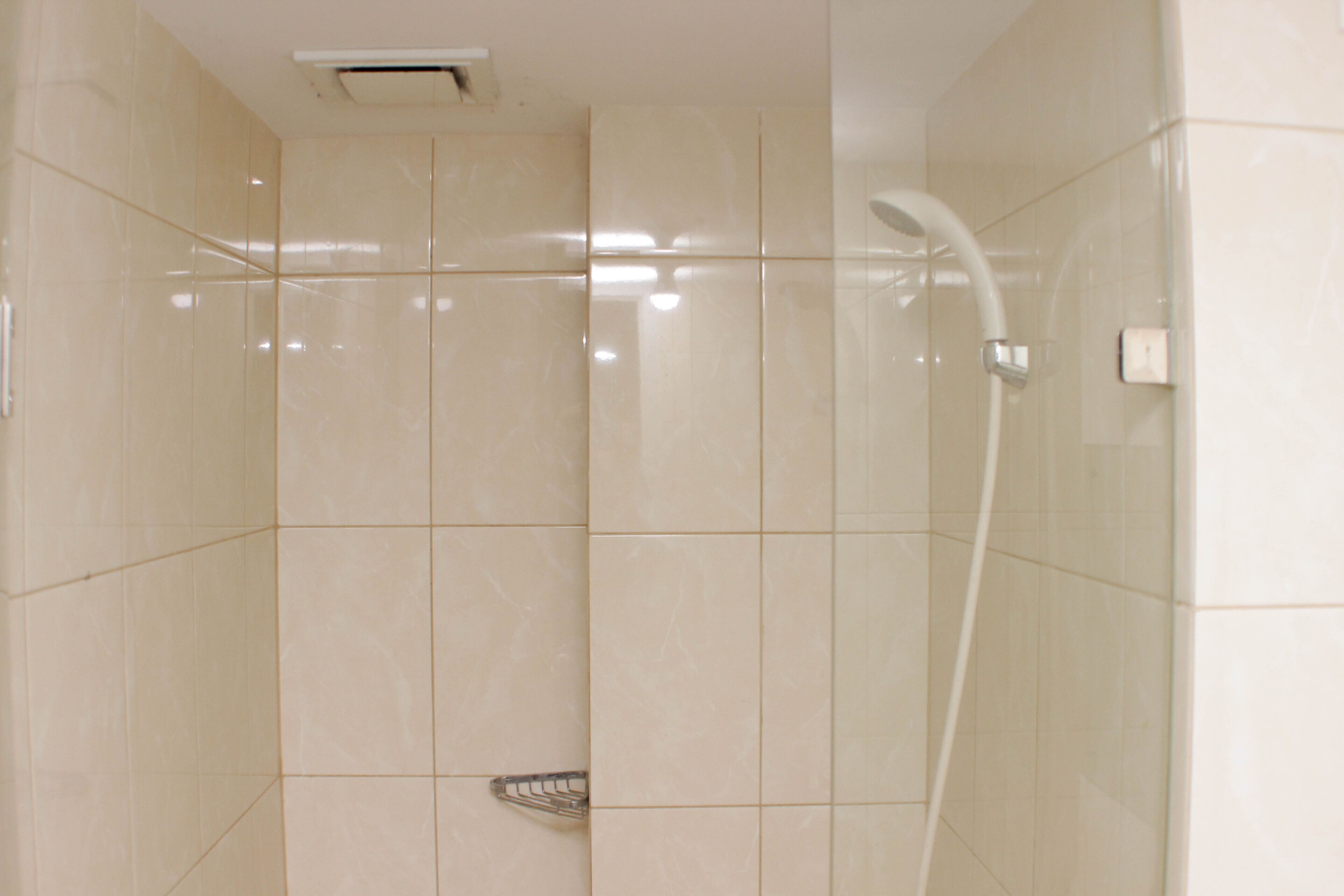 Un baño moderno con ducha, paredes azulejadas y desagüe visible.