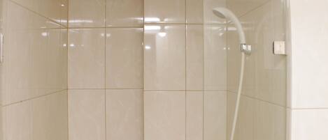 Un baño moderno con ducha, paredes azulejadas y desagüe visible.