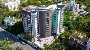 Un hotel moderno a più piani, immerso nel verde con vista sull'oceano.