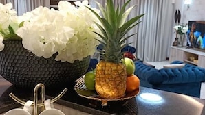 Una cucina moderna con un piano di lavoro nero, fiori bianchi, un'ananas e una ciotola di frutta.