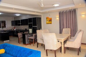 A modern living room with a dining area, a kitchen in the background, and a large window with curtains. - Stay.Plus Antalya Luxury Apartment (Mombasa)