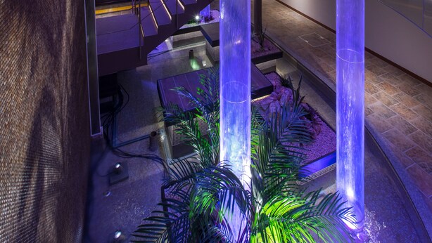 A modern interior with a central atrium featuring tall, illuminated columns, a staircase, and a seating area with plants. - HOTEL ZEN RIKYU CHIBA-SHIROI (Shiroi)