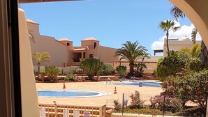 Un balcone con mobili in vimini, una piscina e palme.