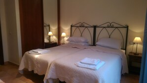 Un letto matrimoniale con testiera in metallo, due comodini con lampade e una porta in legno.