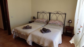 A double bed with a metal frame, two bedside tables, and a nightstand with a lamp.
