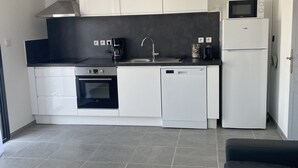 Una cocina moderna con armarios blancos, una encimera negra, un microondas, un fregadero y un lavavajillas.