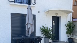 Un edificio con un balcón, una puerta y una planta en maceta.