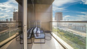 A balcony with a sofa and chairs, a small table, and a view of the cityscape. - JVC Studio park view fully equipped - 360 vacation (Dubai)