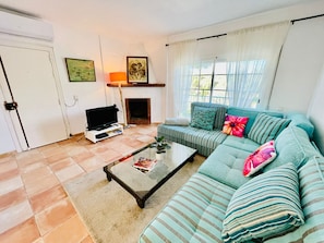 Una sala de estar con sofá, mesa de centro, televisor y chimenea.