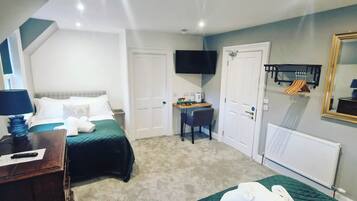 A hotel room with two beds, a desk, a television, and a mirror.