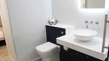 Une salle de bain moderne avec des toilettes blanches, un meuble noir et un lavabo blanc doté d’une grande cuve.