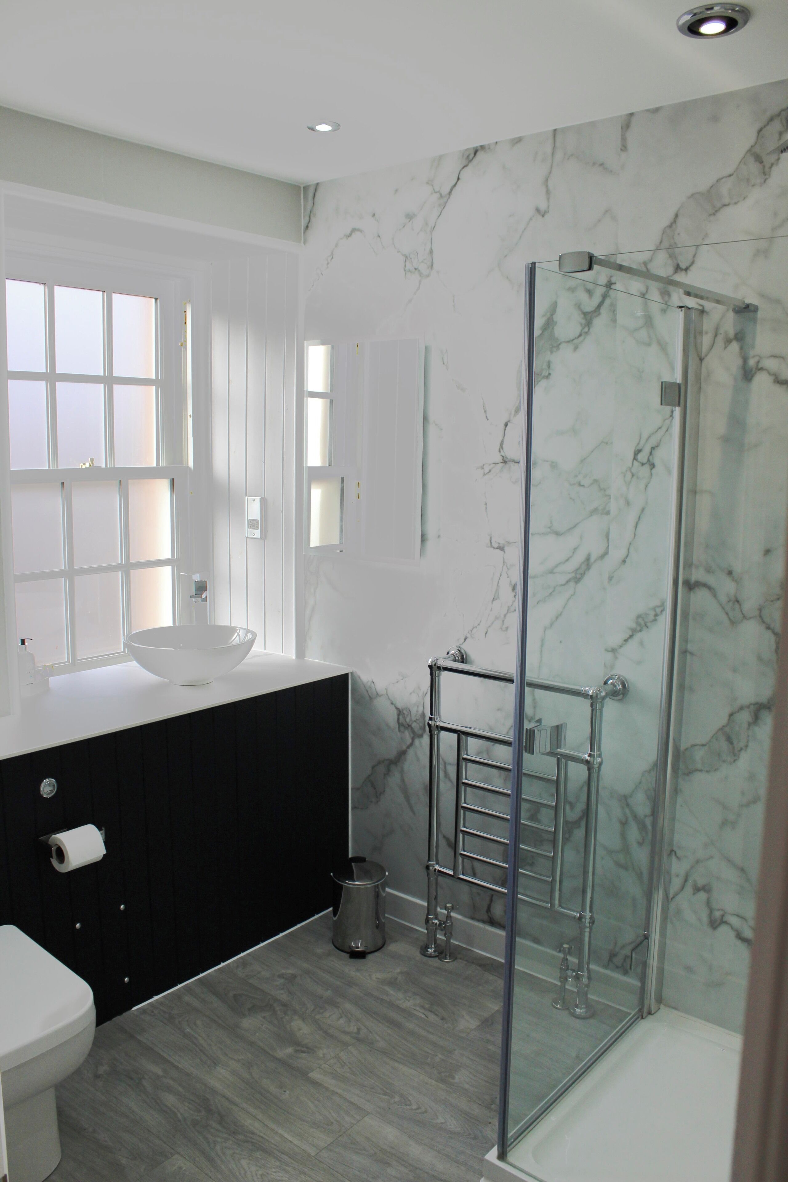 A modern bathroom with a glass-enclosed shower, a white sink, and a black vanity.