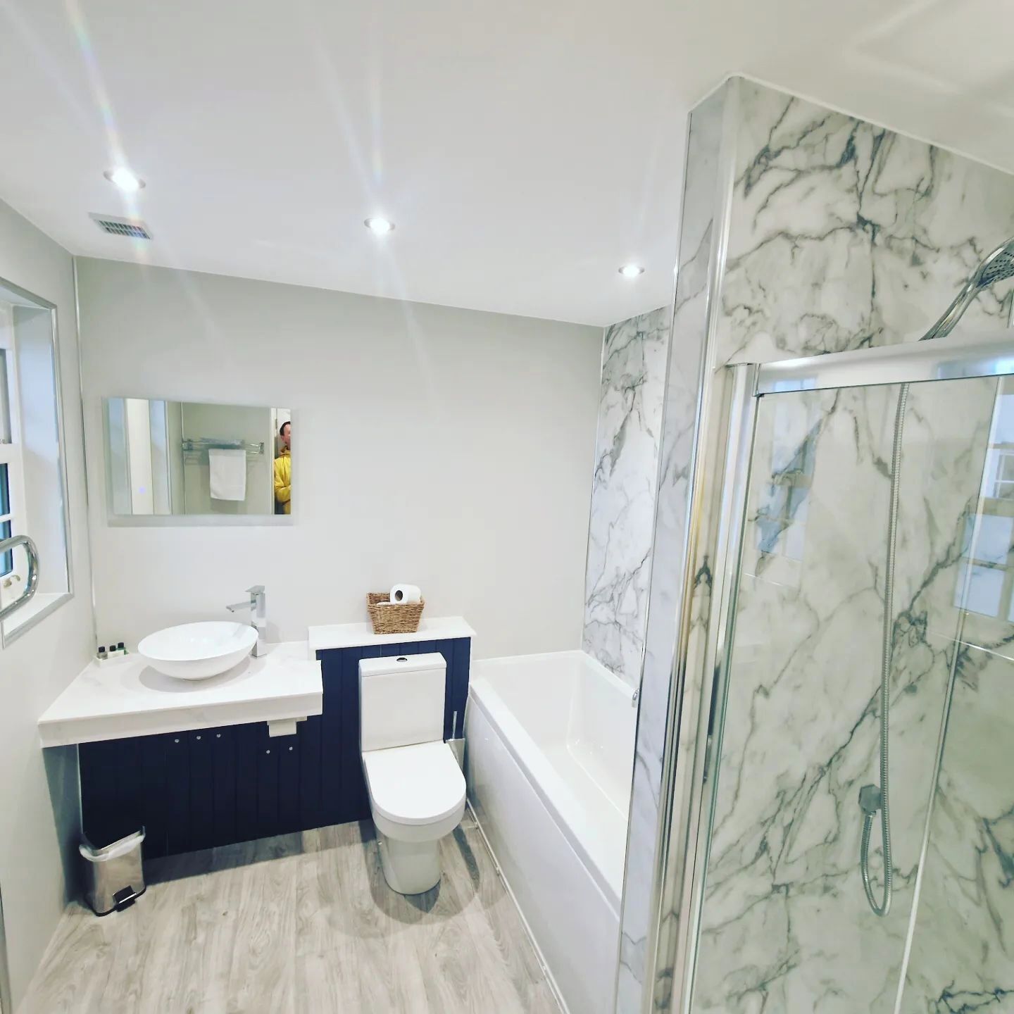 Een moderne badkamer met een wit wastafel, toilet en een douche met glazen wanden.