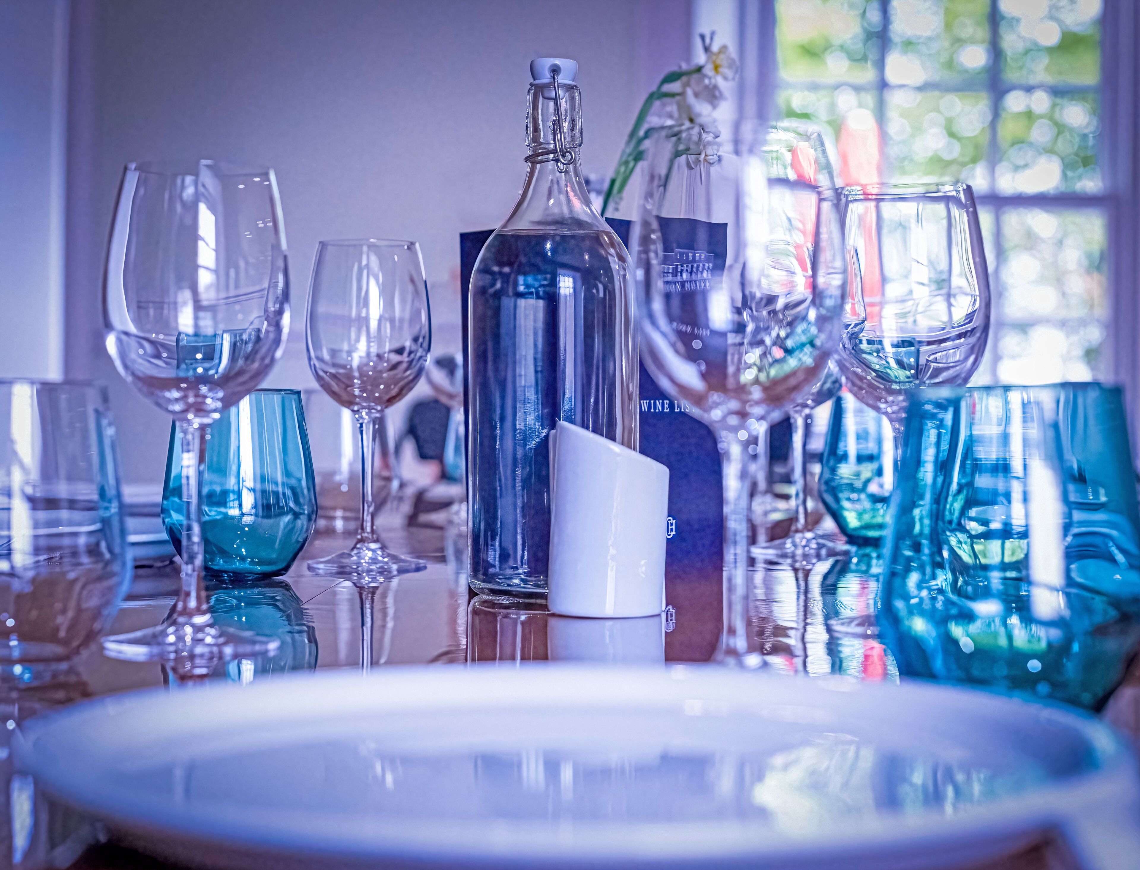 A table set with various glassware and a bottle, likely for a dining event.