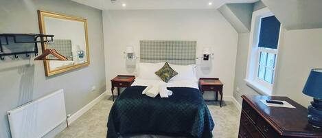A bedroom with a bed, bedside tables, a dresser, a mirror, and a radiator.