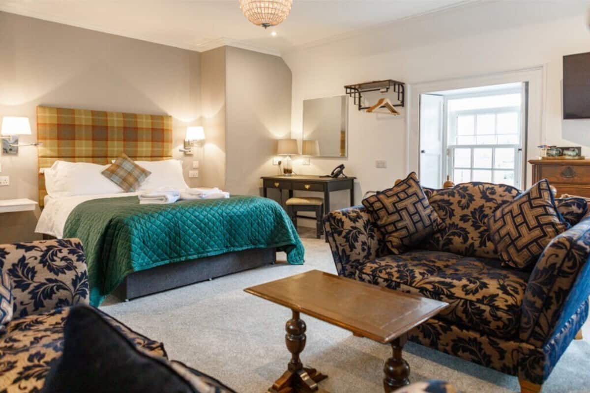 Ein Hotelzimmer mit einem Bett, zwei Sofas, einem Tisch und einer Kommode.